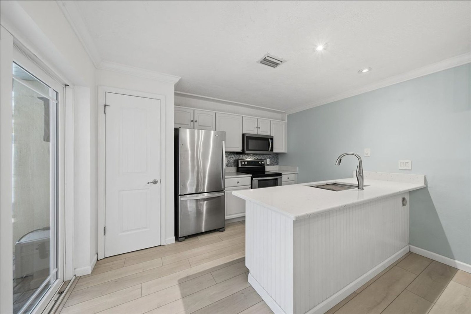 Remodeled kitchen with quartz counters, large undermount sink, and stainless refrigerator
