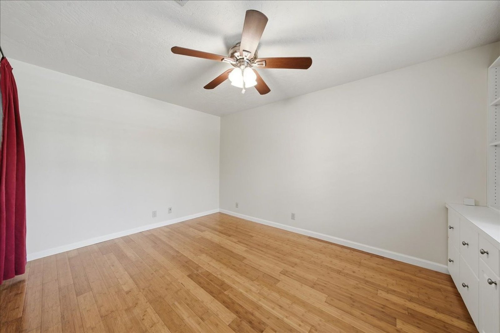 Second bedroom with bamboo floors and red accent curtains at 8760 Live Oak Ct