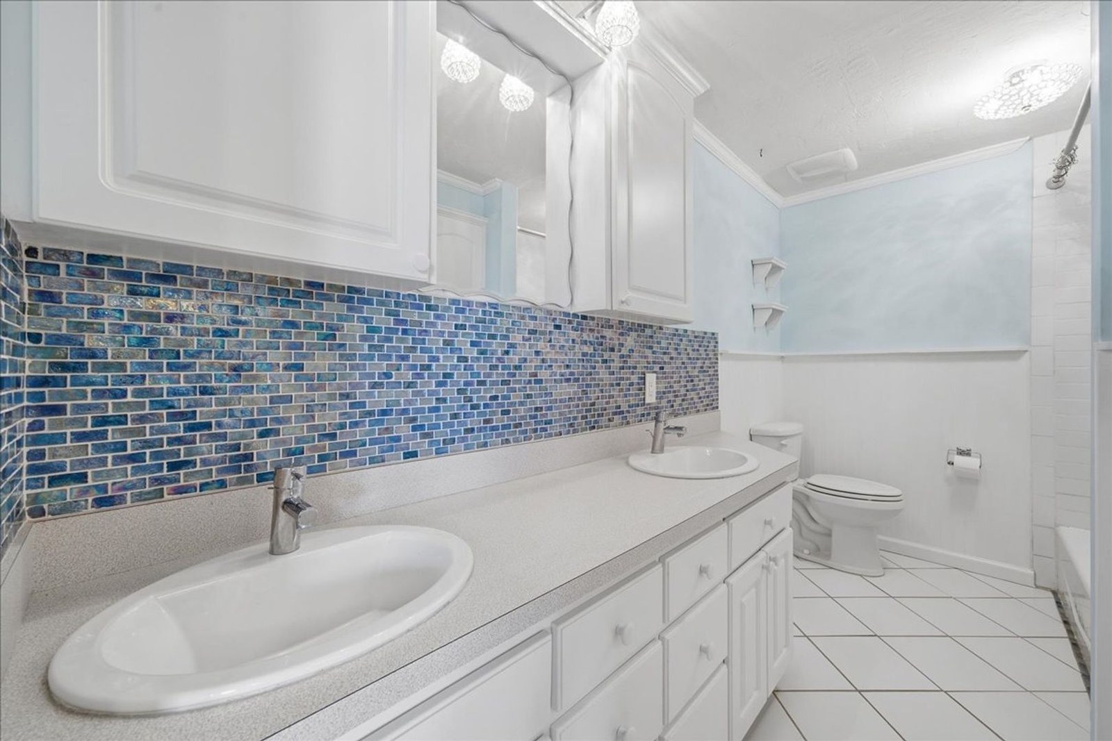 Updated bathroom with blue glass-tile accent wall and white vanity