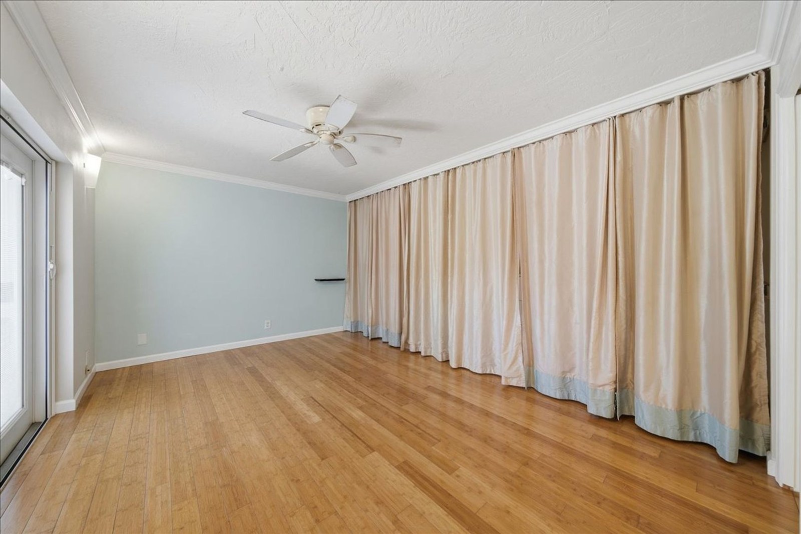 Bedroom with bamboo flooring, ceiling fan, and curtained closet at 8760 Live Oak Ct