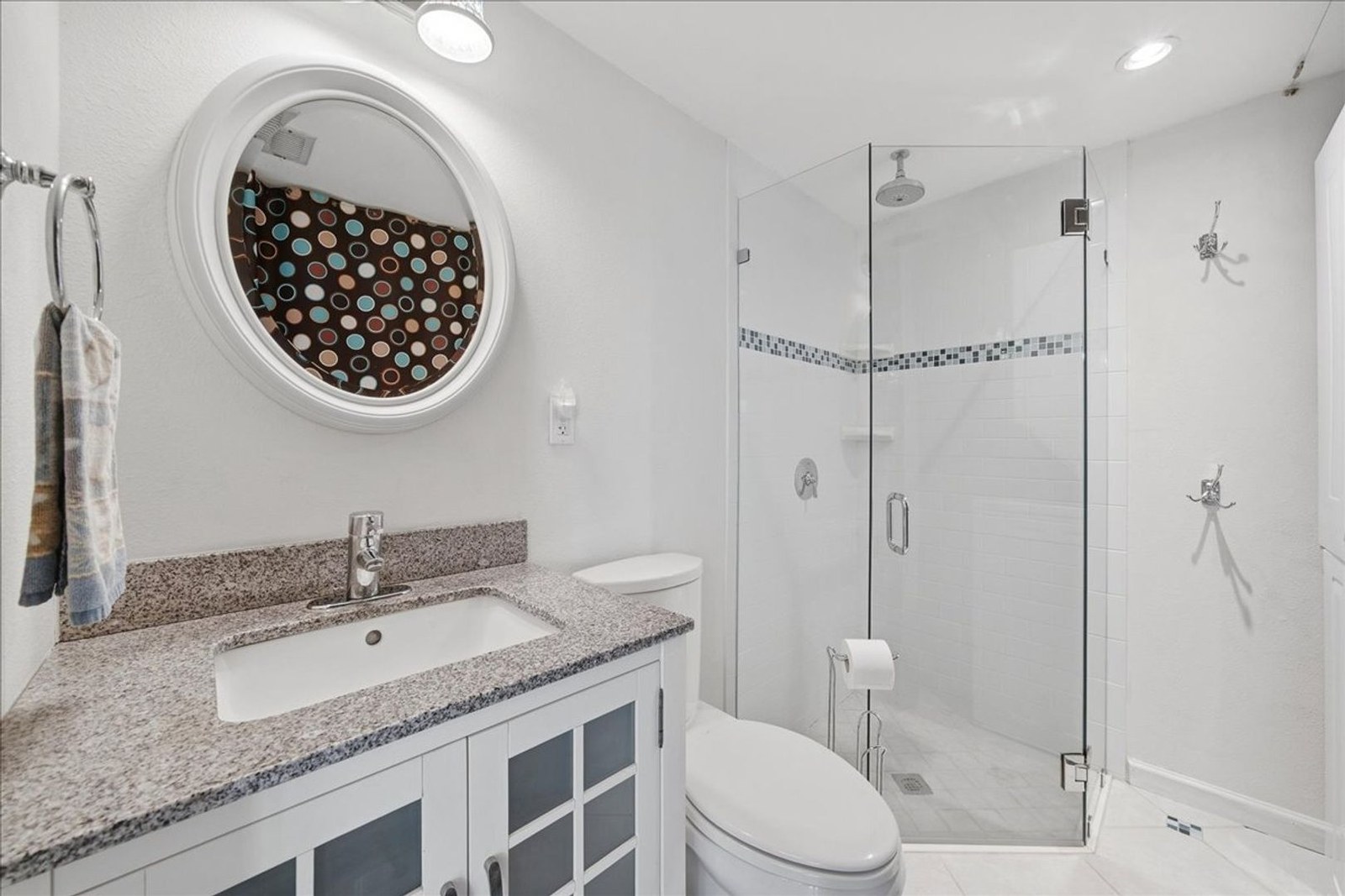 Updated bathroom with round mirror, granite vanity, and glass shower at 8760 Live Oak Ct