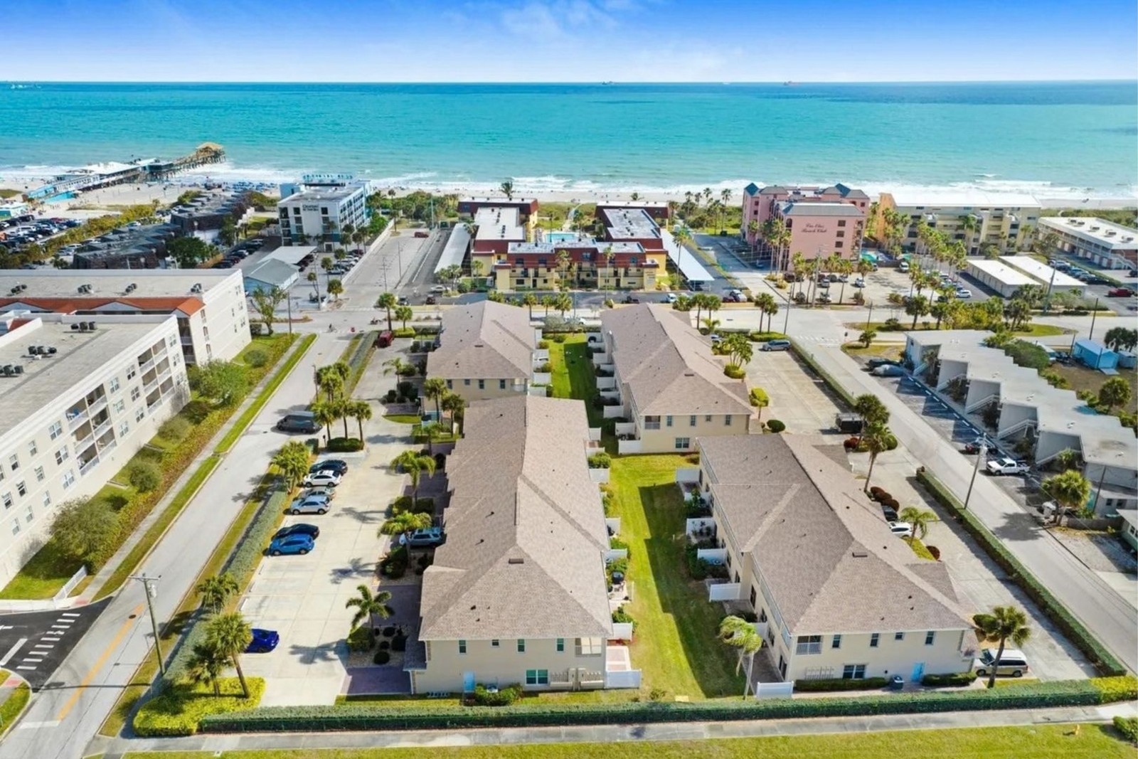 Aerial view of Villas by the Sea at 5201 Ocean Beach Blvd with the beach and Cocoa Beach Pier beyond