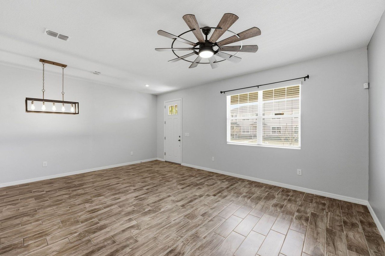Bright living room with large windows and ceiling fan