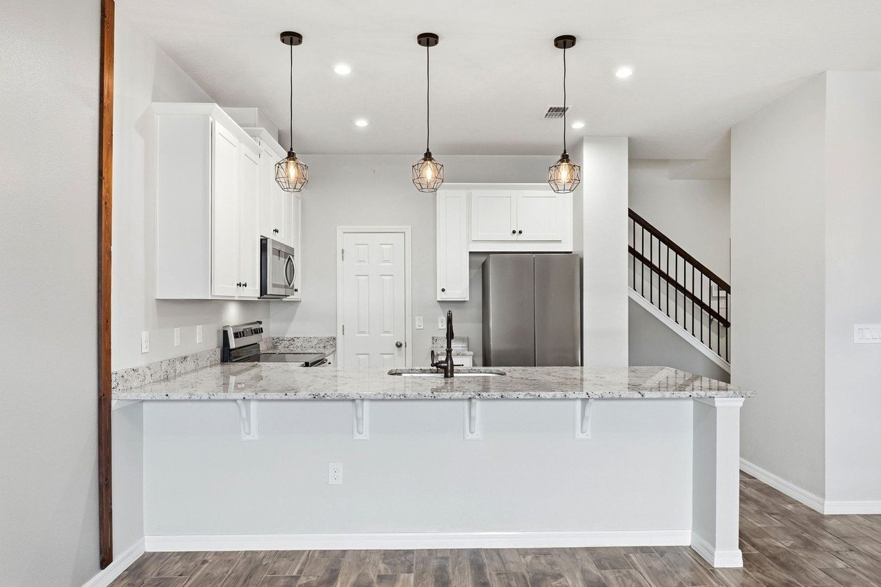 Kitchen with pendant lighting, white cabinetry, and island bar seating