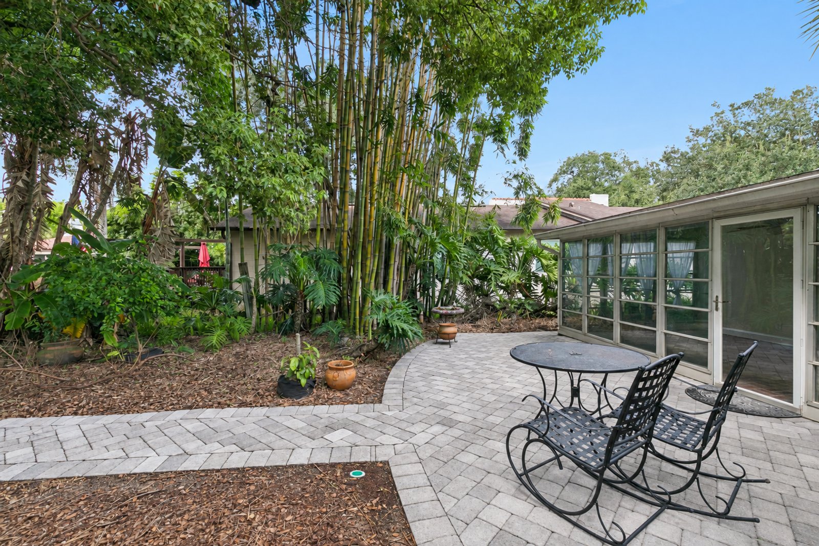 Paver patio with bamboo and tropical landscaping beside the Florida room