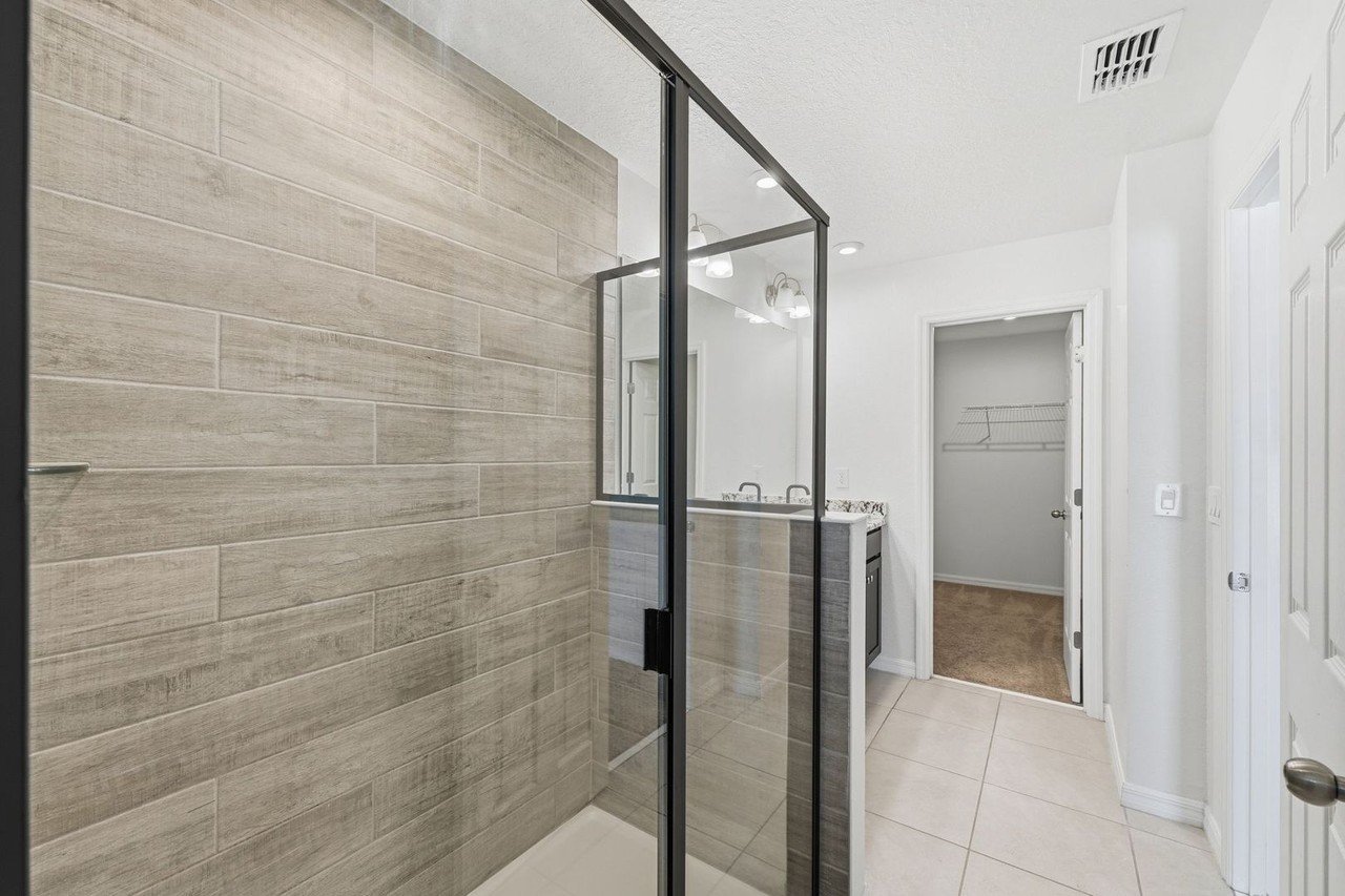 Glass-enclosed tiled shower in the primary bath
