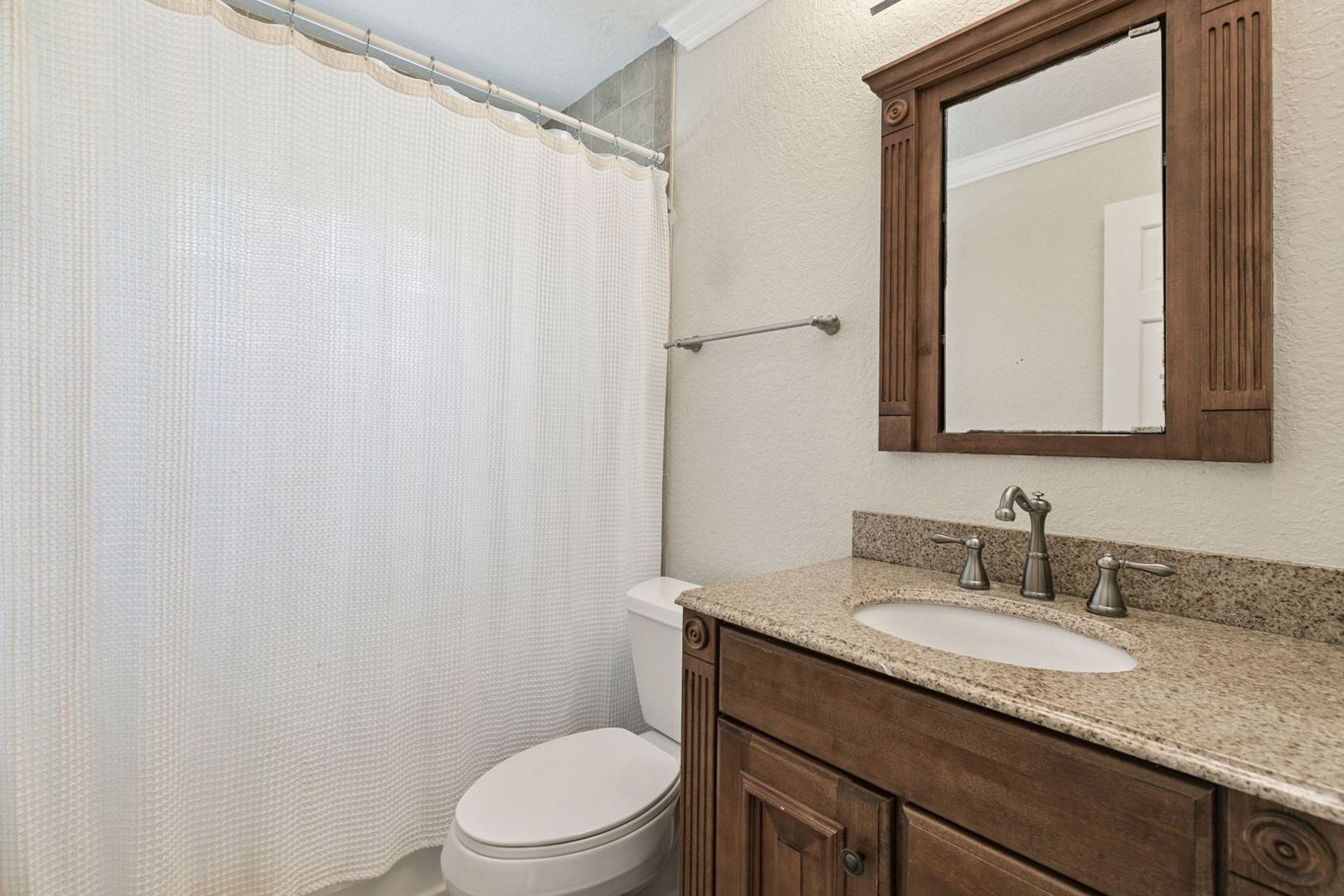 Primary ensuite bathroom with granite vanity and tub/shower combination
