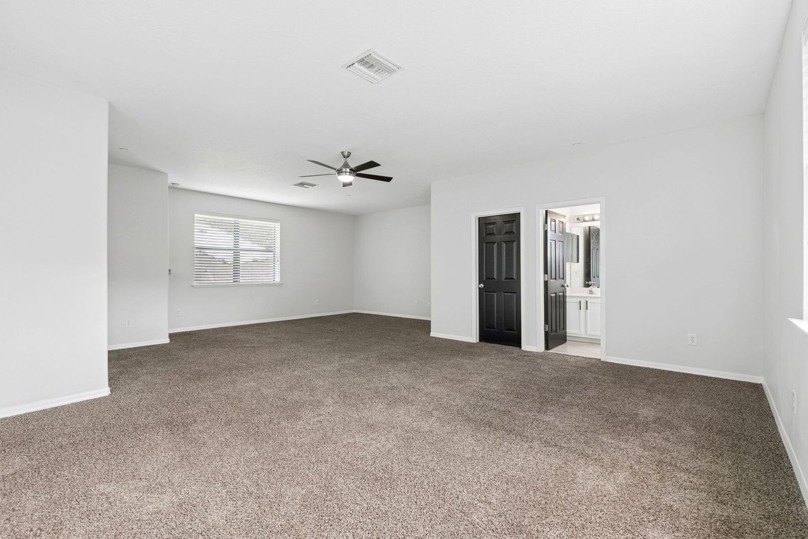 Primary bedroom with ceiling fan and en-suite entry
