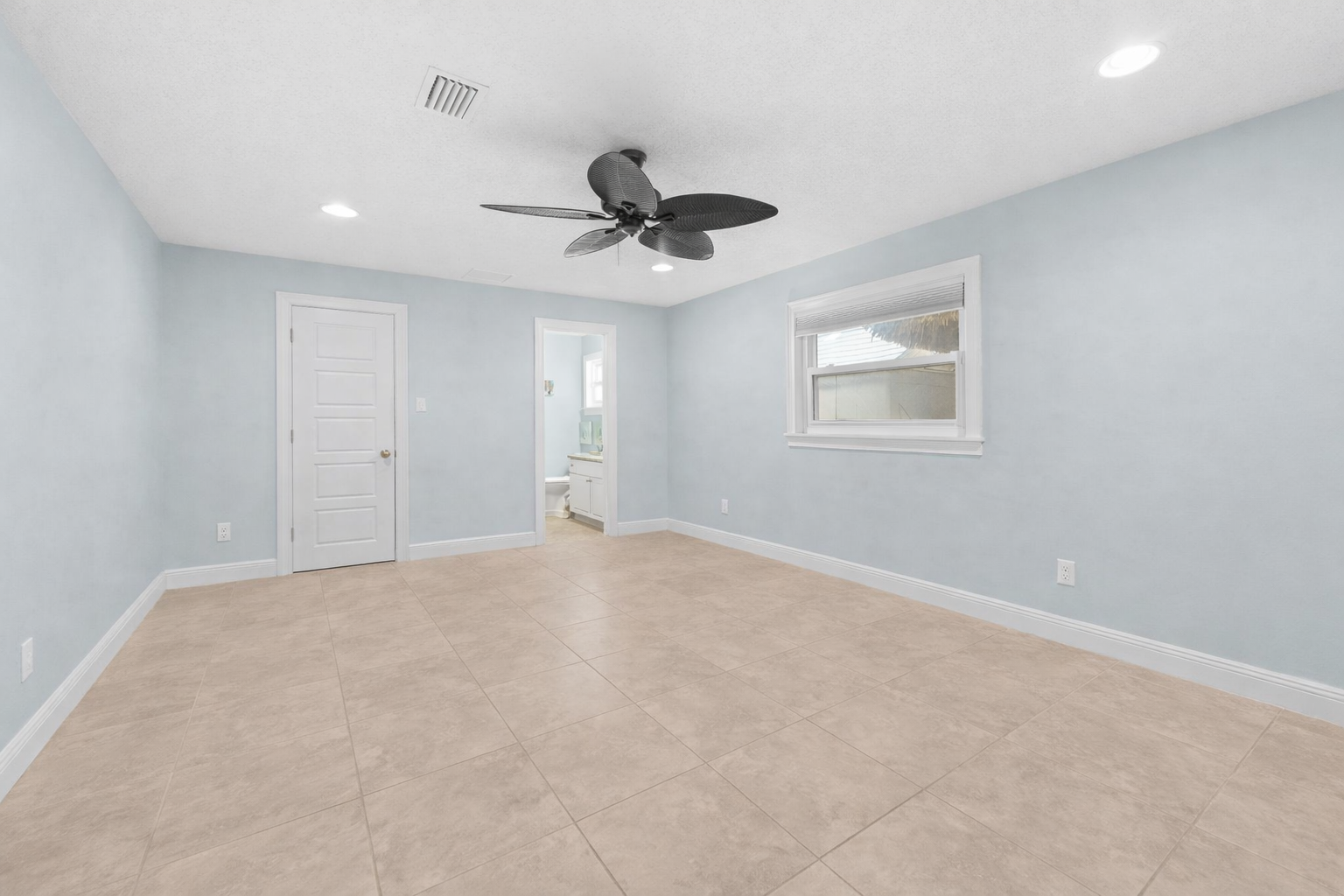 Primary bedroom with en-suite bath access and ceiling fan