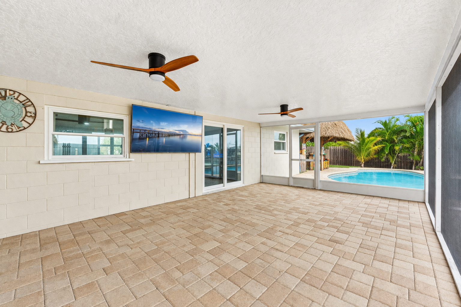 Covered lanai with mounted TV overlooking the pool