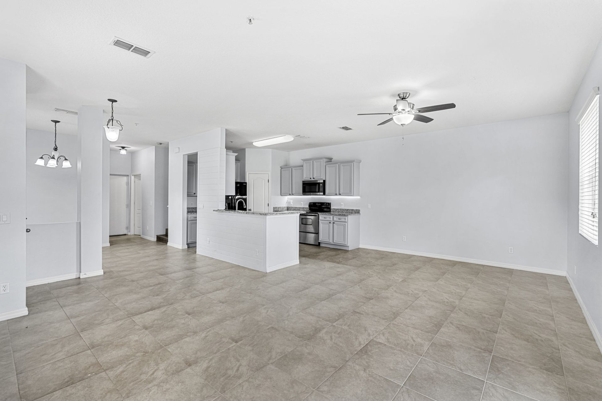 Open great room with tile floors and ceiling fan
